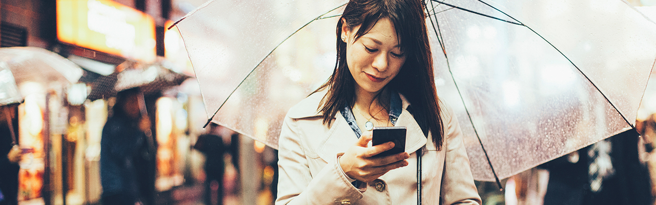 Woman using mobile under umbrella